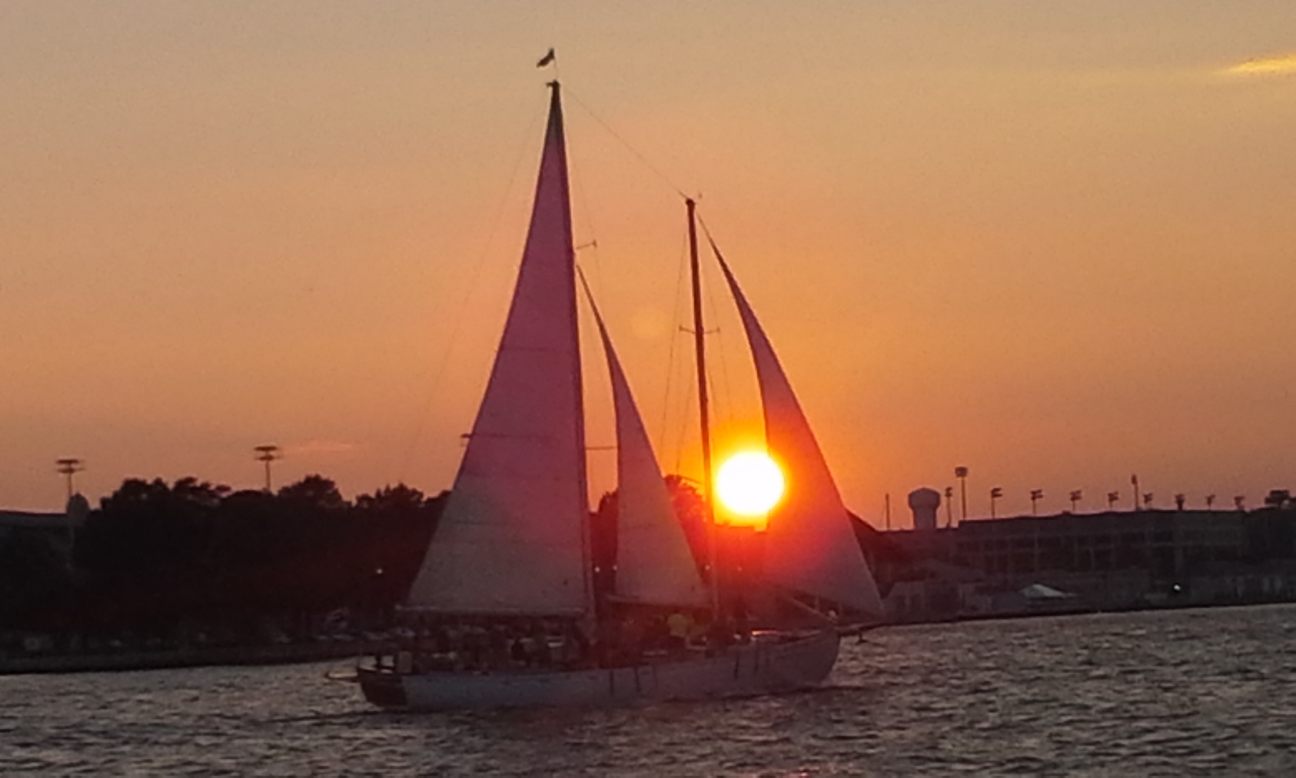 The sunset blazing from in between the sails of the schooner
