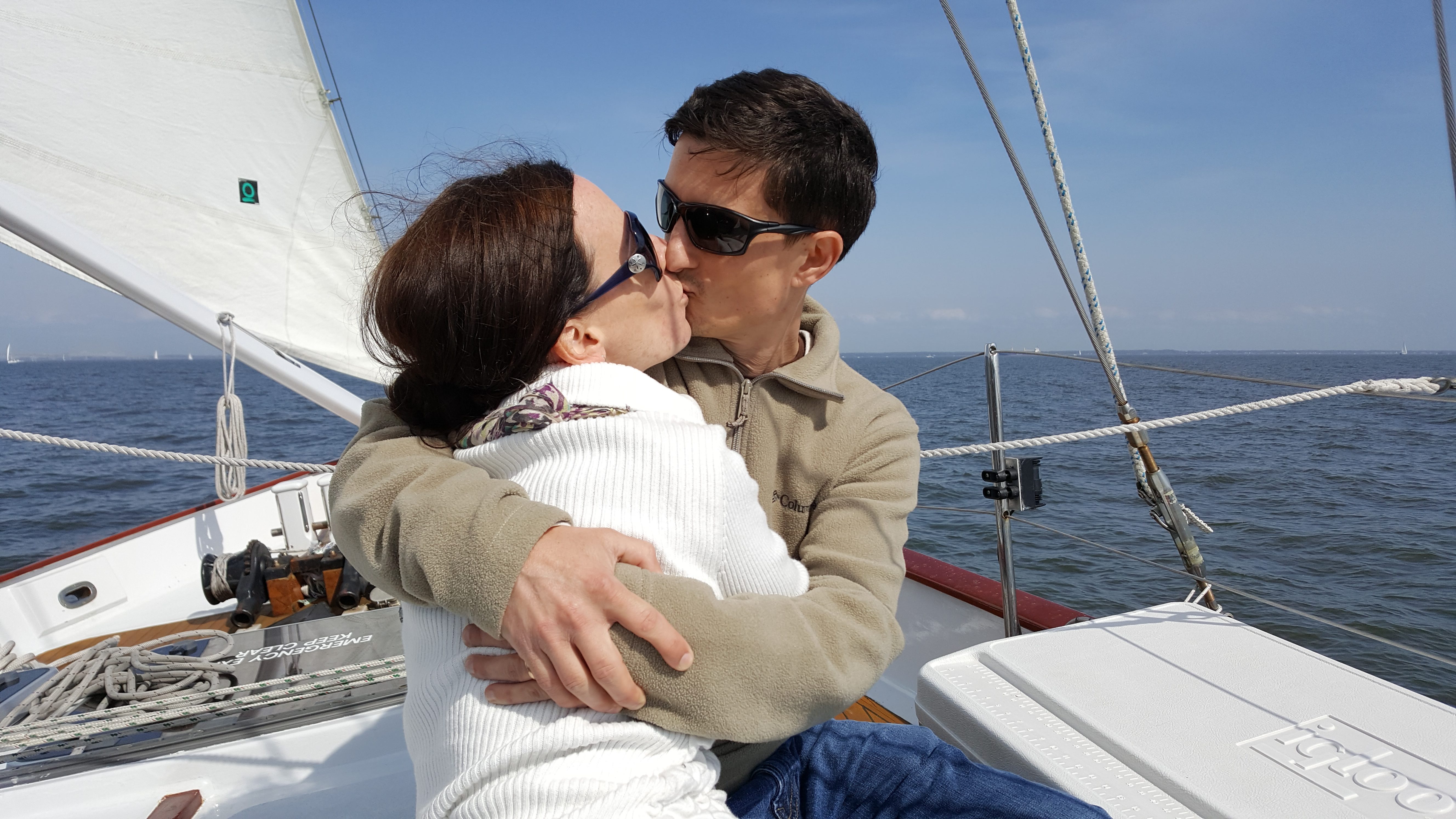 Young couple kissing on boat with blue water and sky