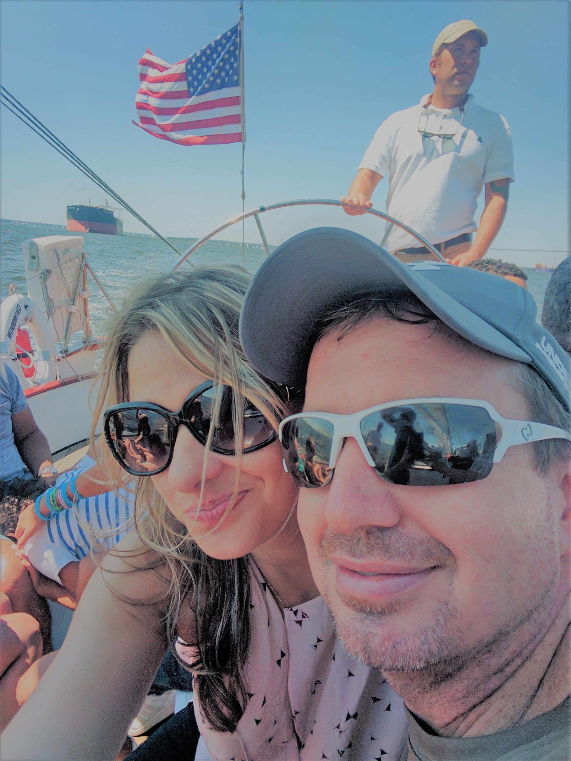 Couple smiling while captain sailing the boat in background