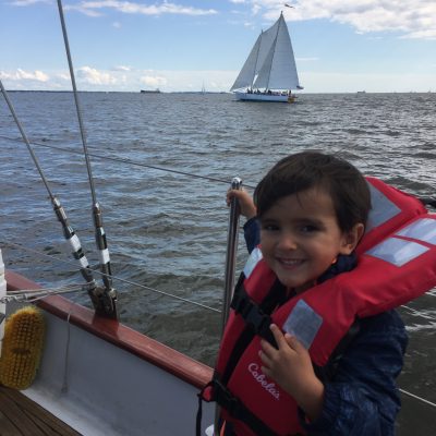Happy little boy on boat with orange life vest