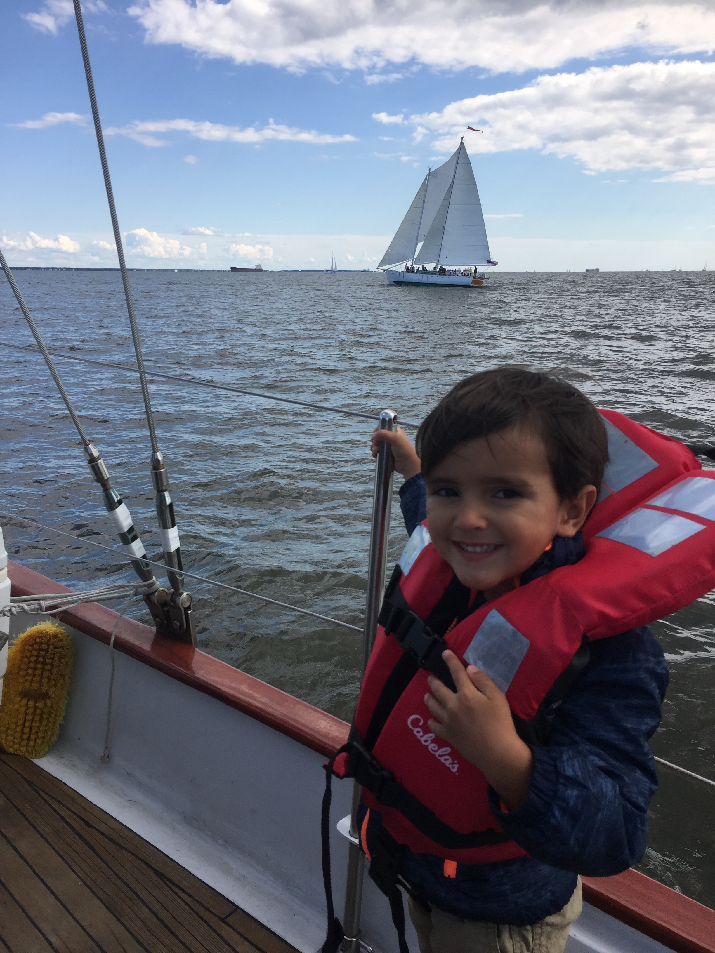 Happy little boy on boat with orange life vest