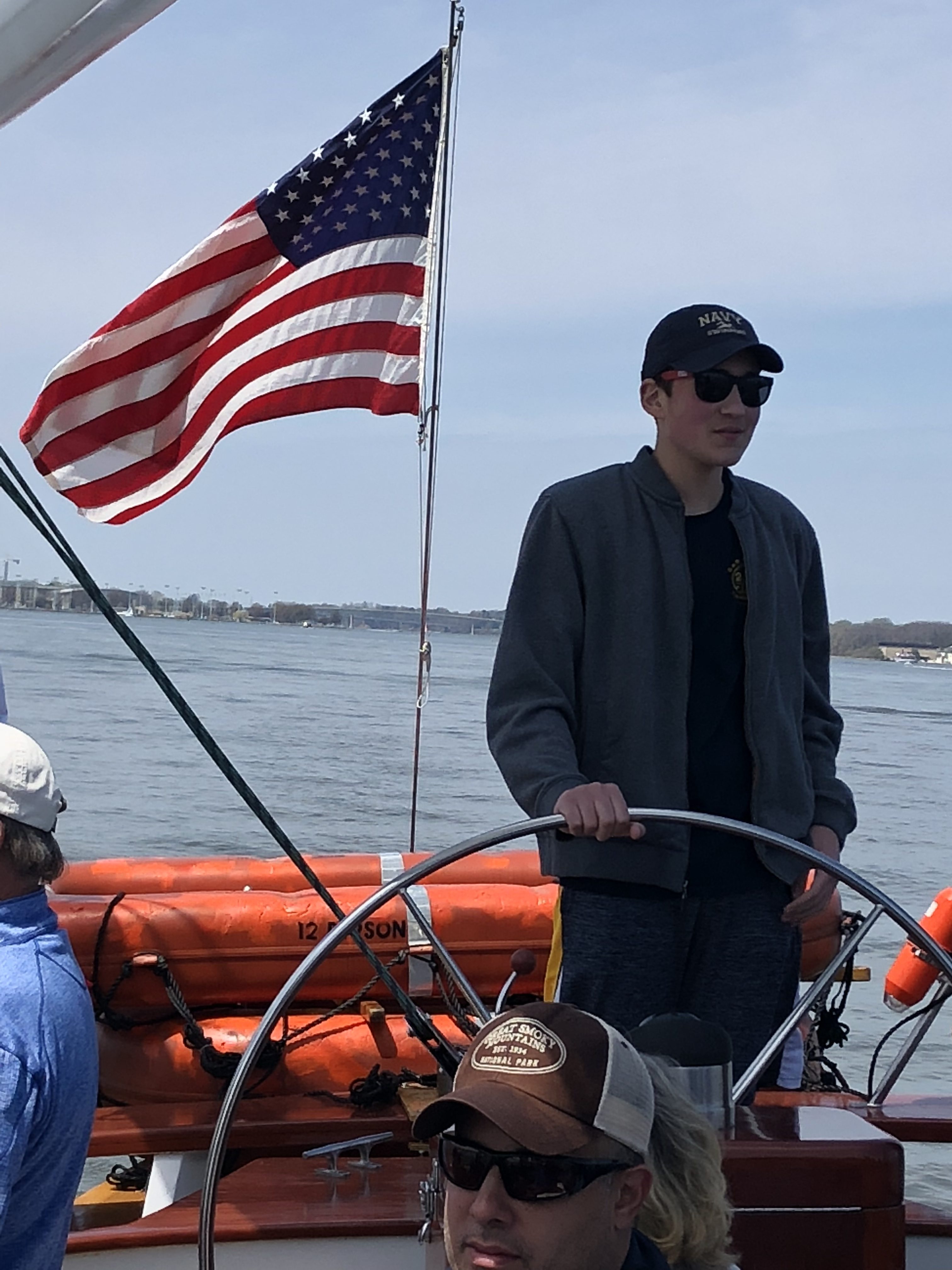 Young man steering the schooner with dark sunglasses on