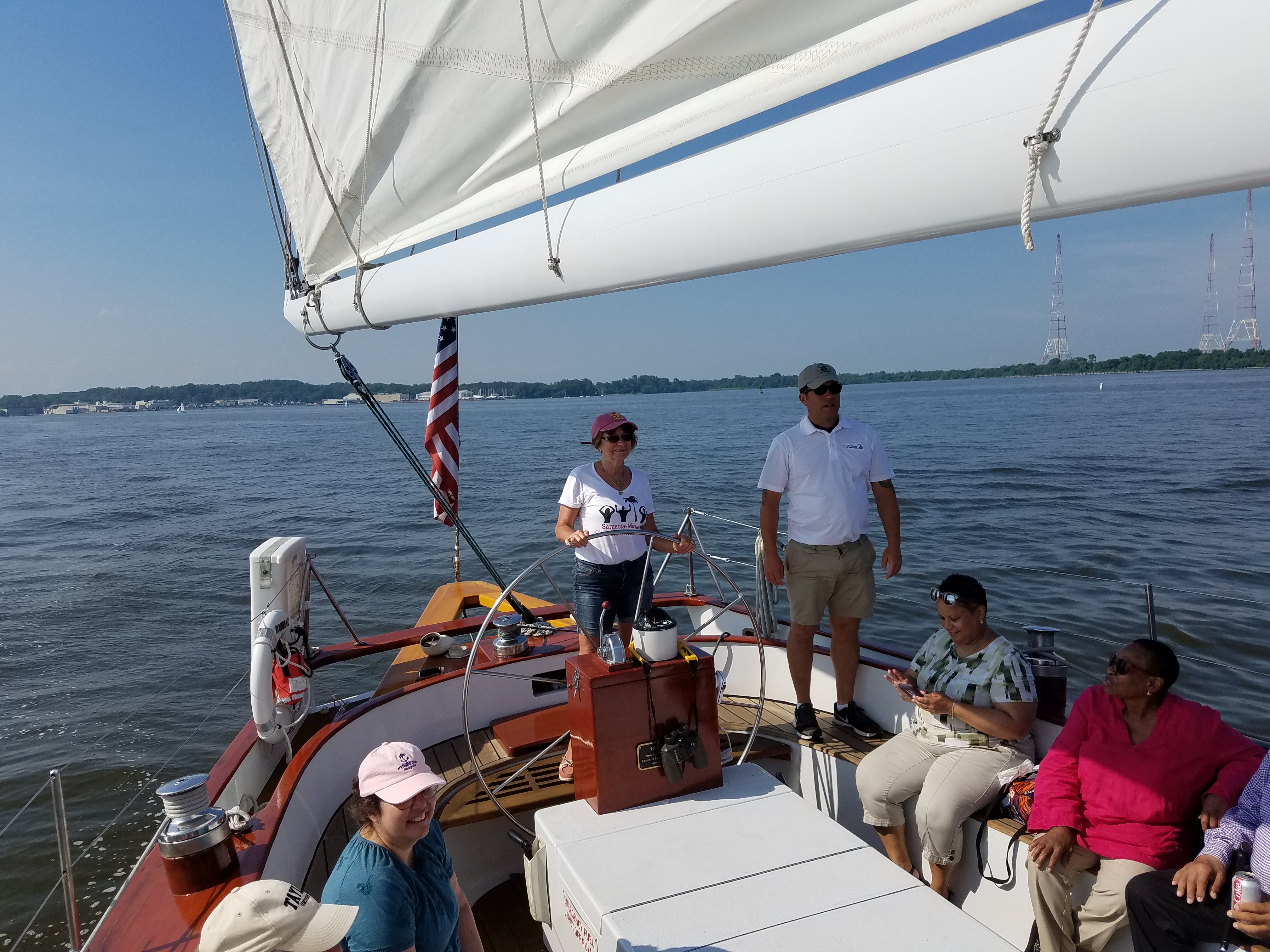 Women steering the schooner with pink hat on as captain stands by