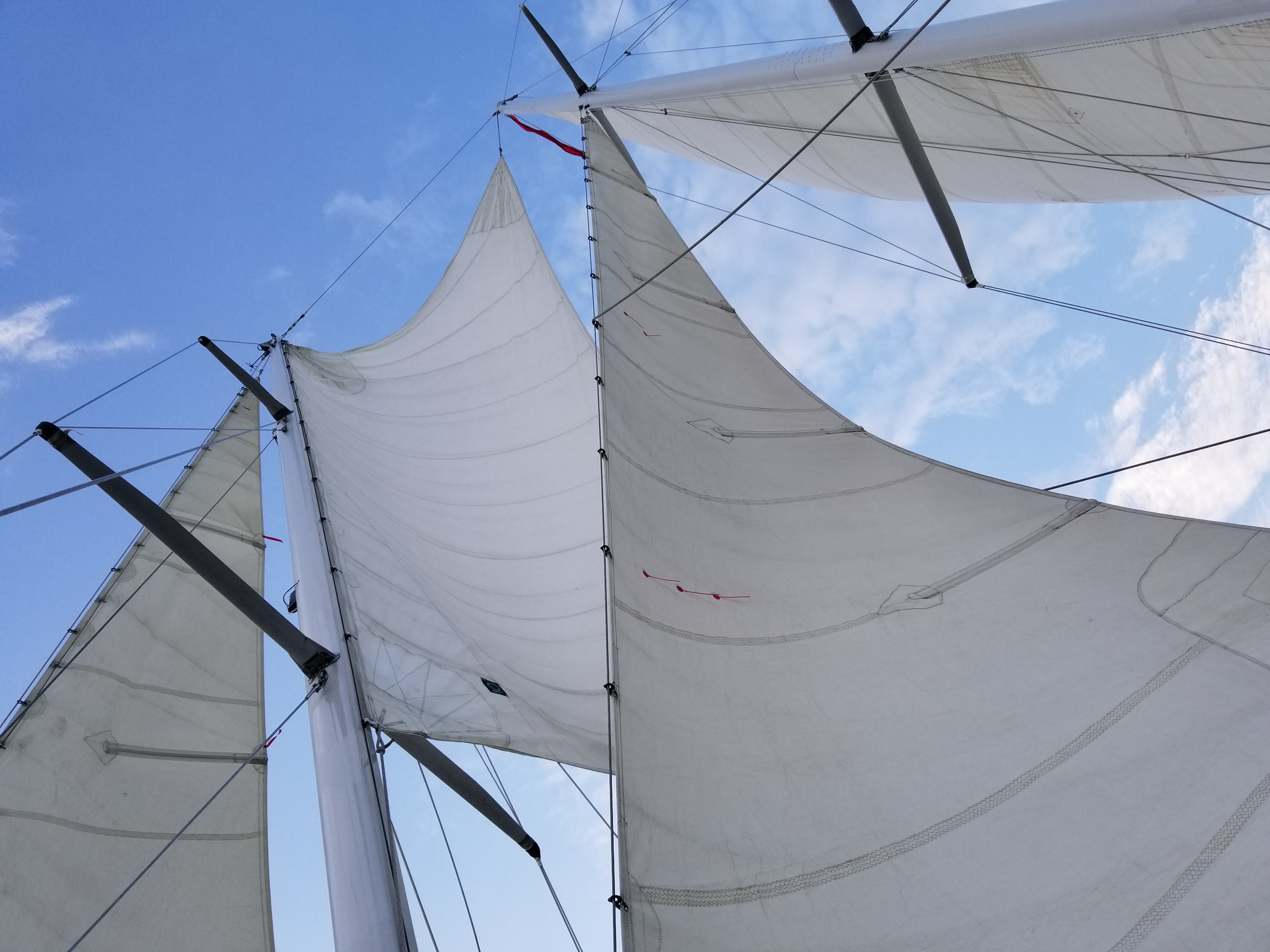 Looking through the sails into blue skies with clouds