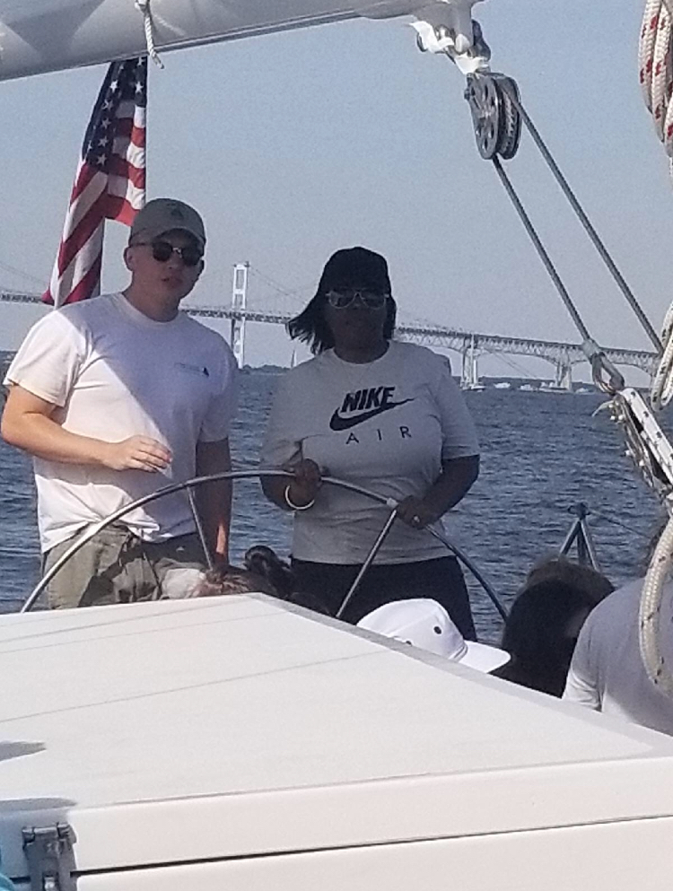 Women steering the boat with guidance from captain