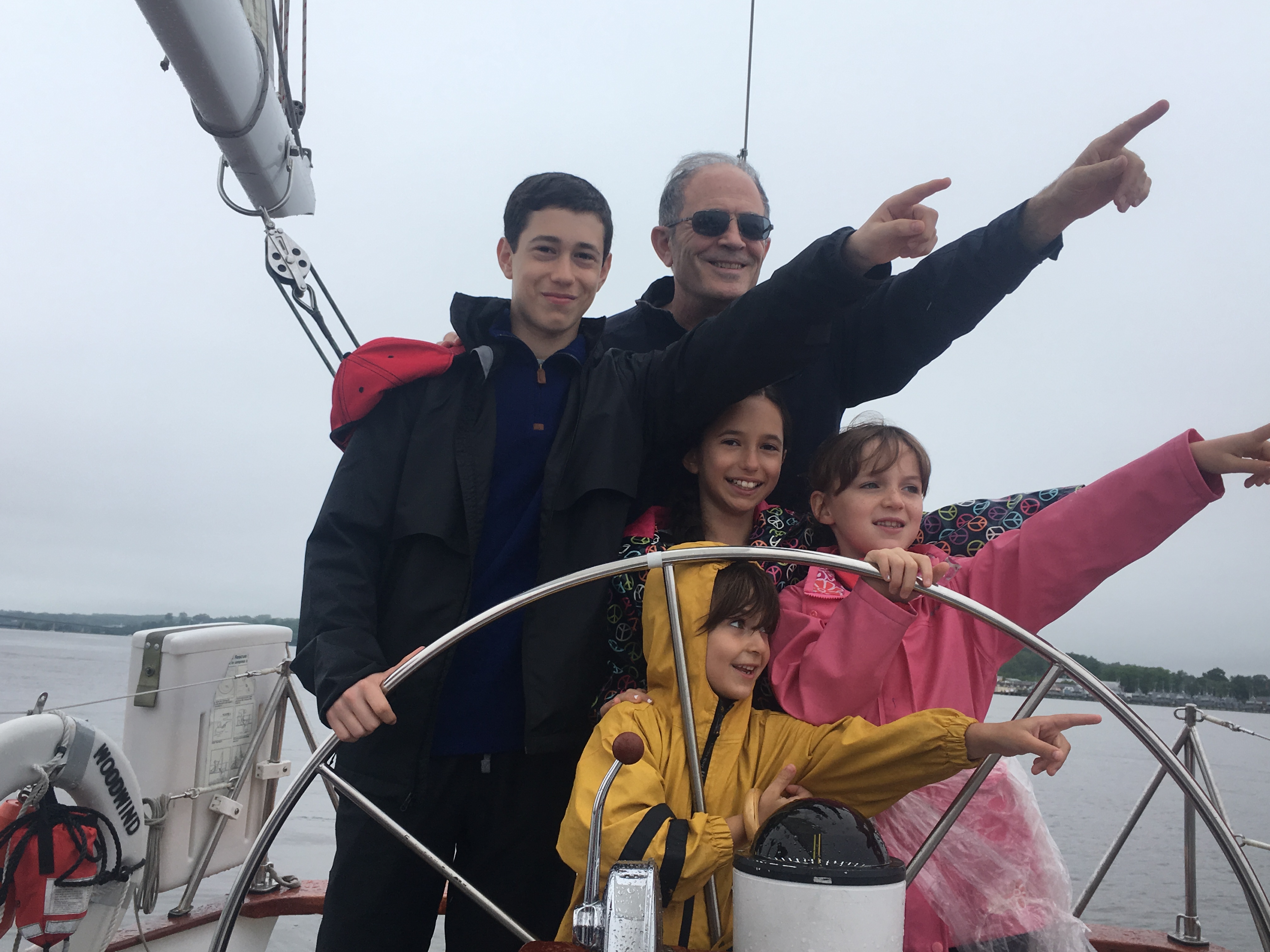 Family of five pointing to the left and steering the boat