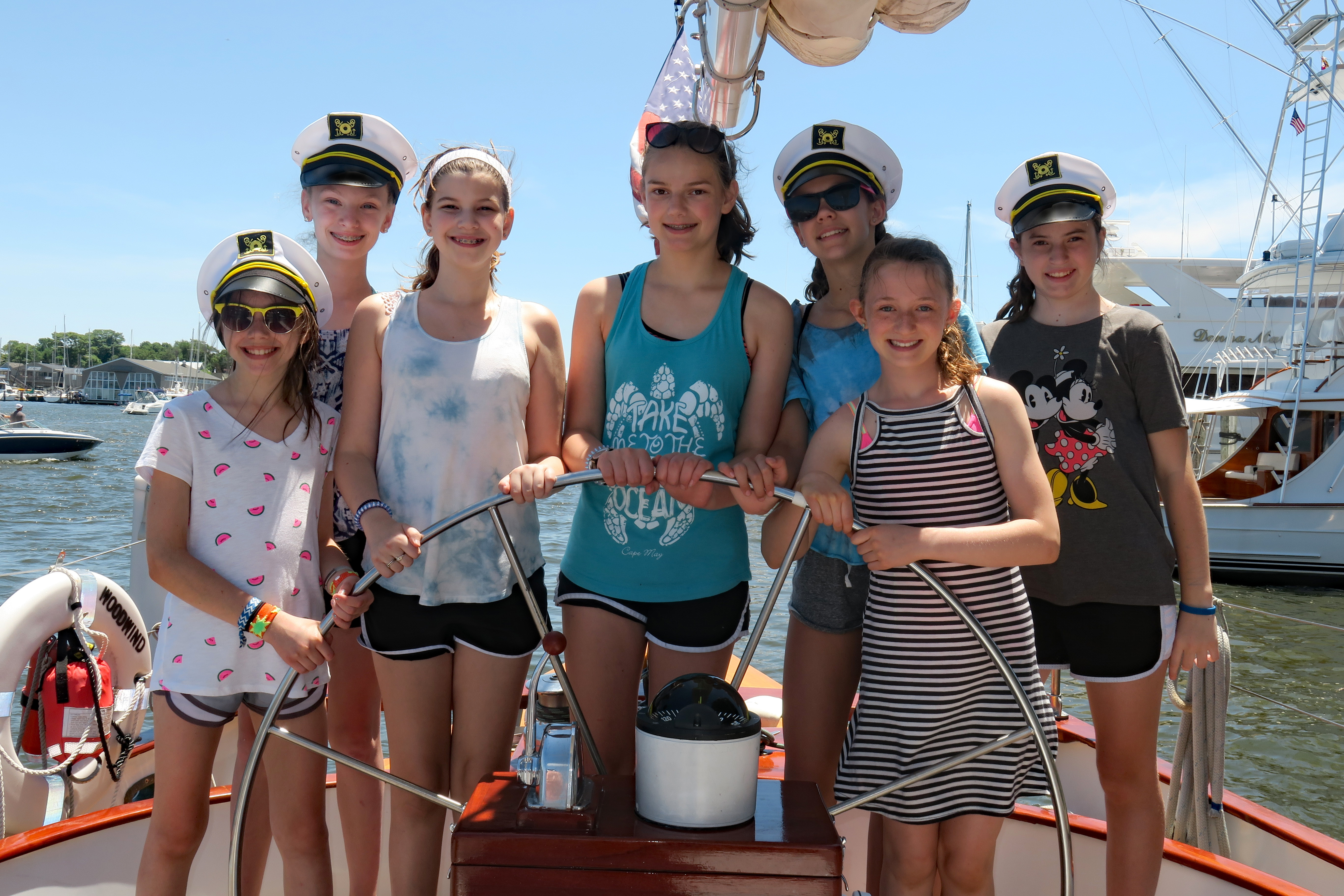 Girl Scout troop learning to sail and sporting captains hats