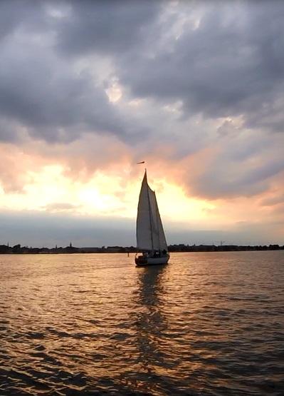 Schooner sailing into the sunset on dark waters
