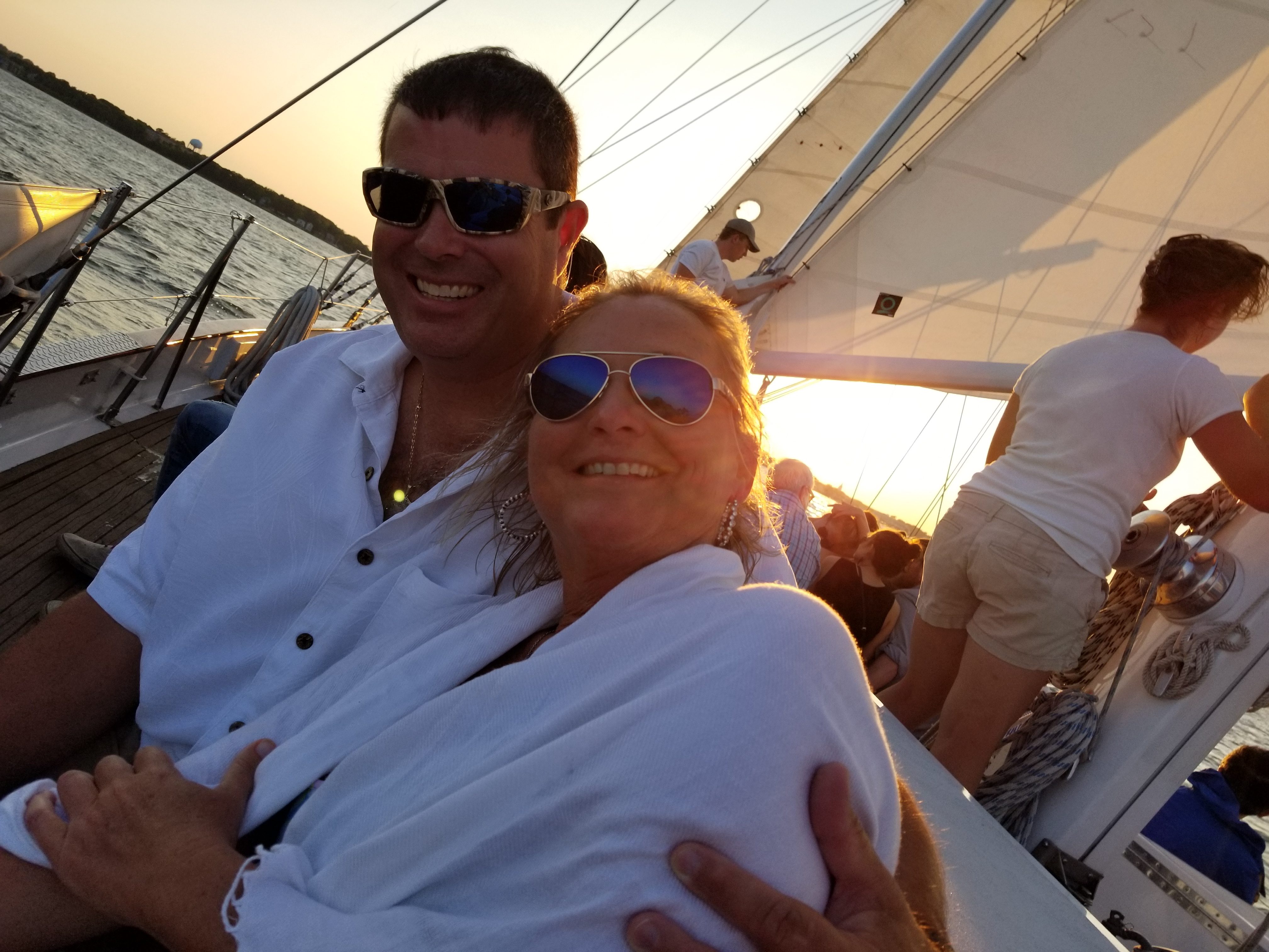 Couple smiling with blue water and sun sailing by