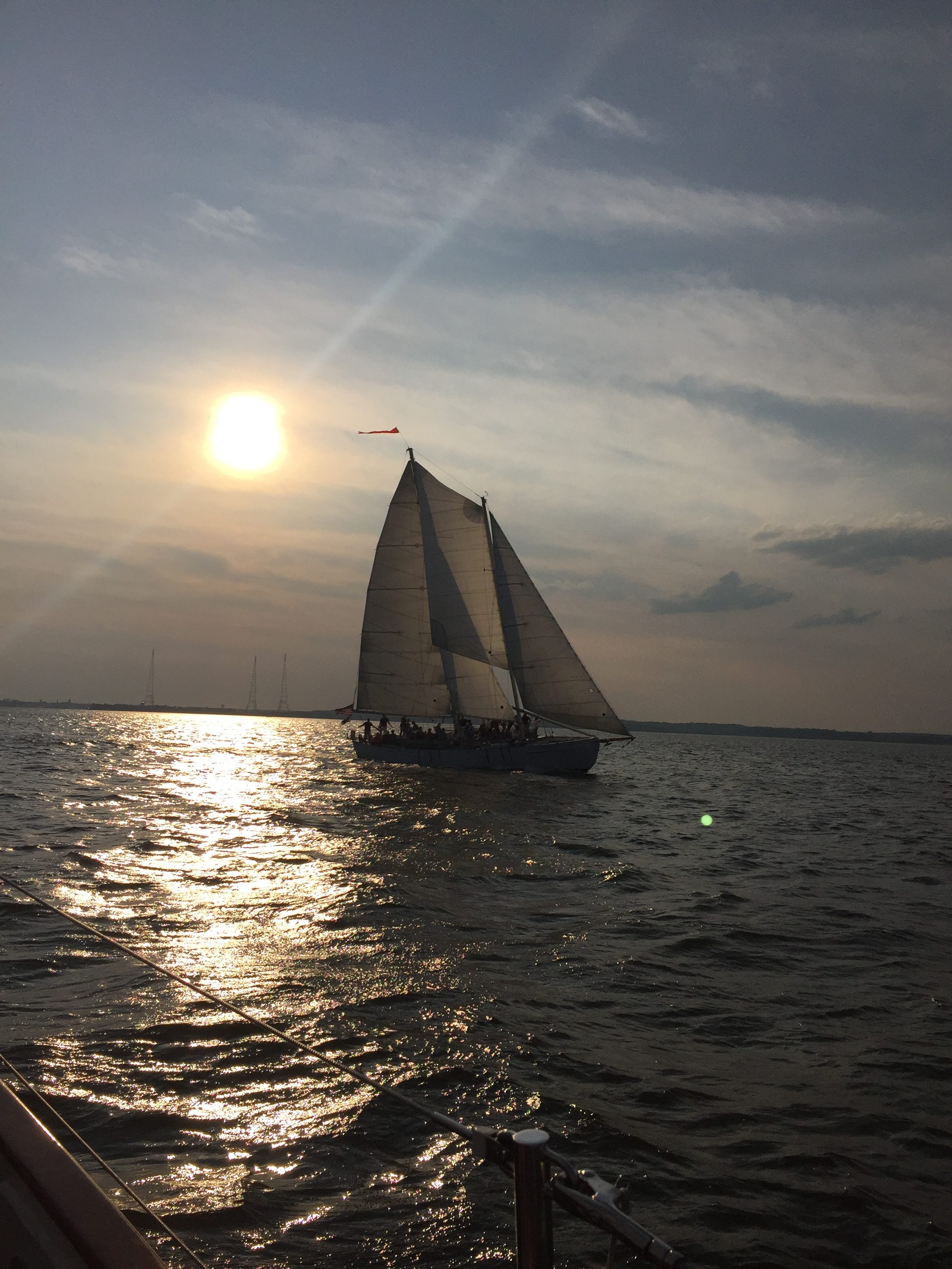 Schooner sailing with bright sunset above dark waters