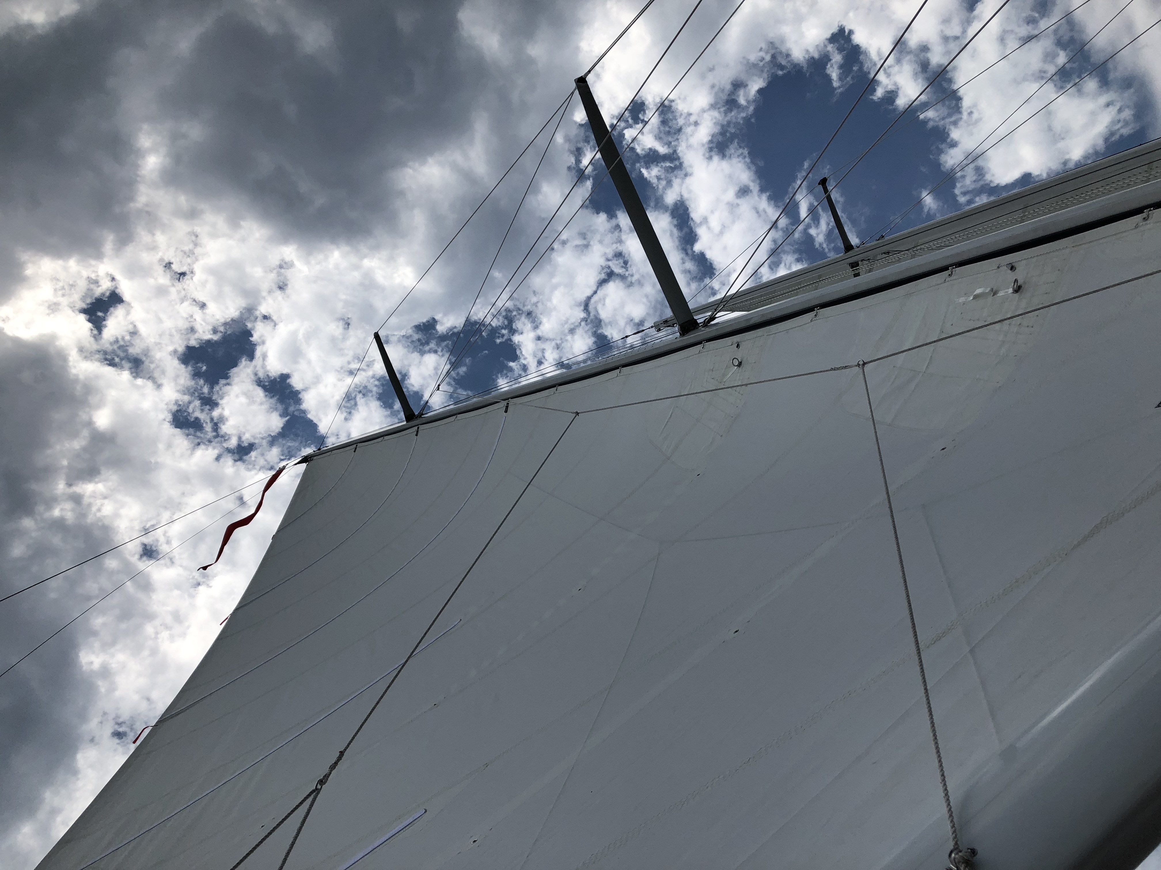 Looking straight up through sails and rigging at blue and white sky