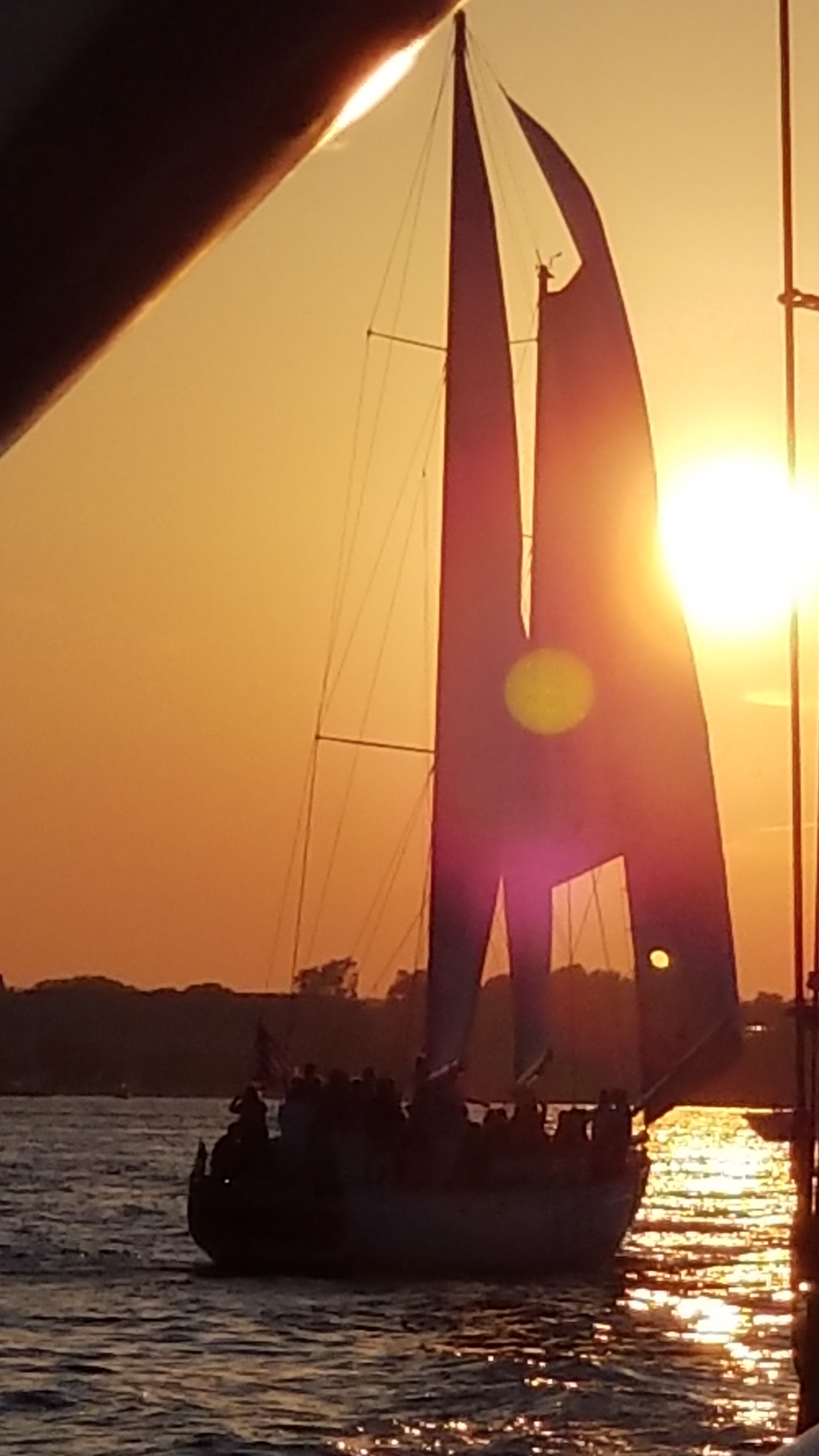 One of the Schooners under sail framed in a bright sunset