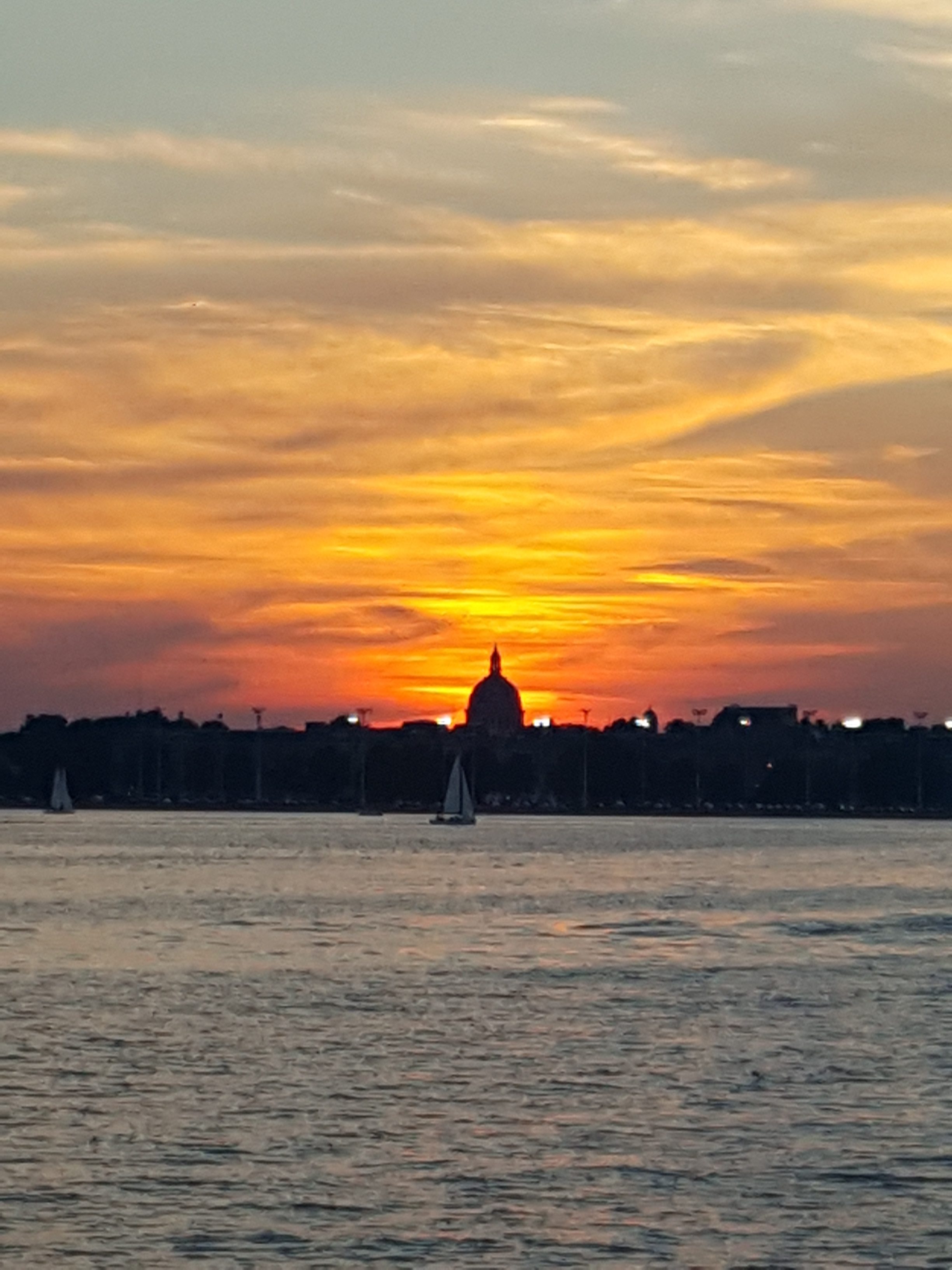 Yellow and Orange sunset shining over the Capital from a blue bay