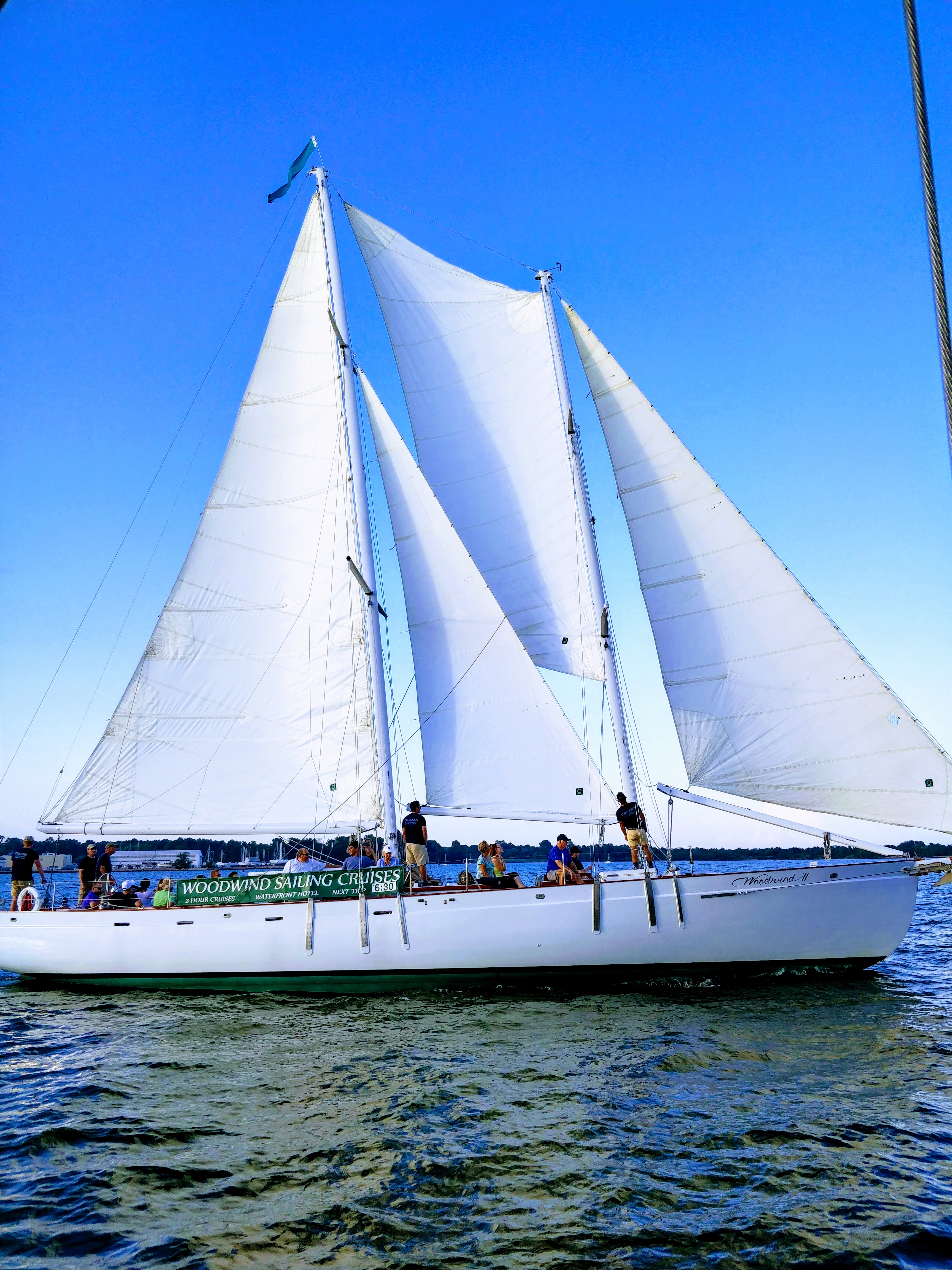 Schooner sailing in bright blue water and skies with guests on board