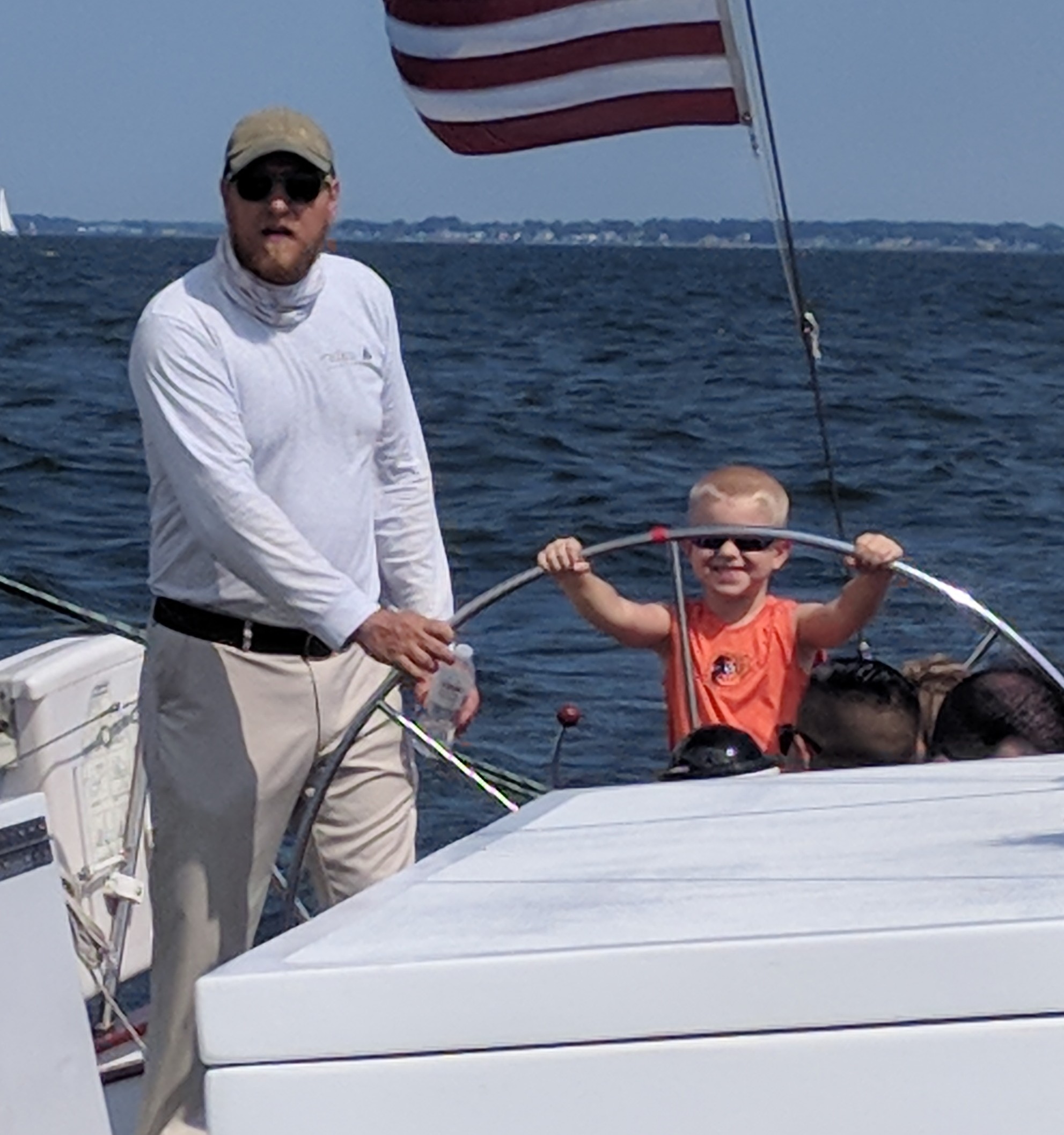Captain helping a young boy with big smile steer the helm