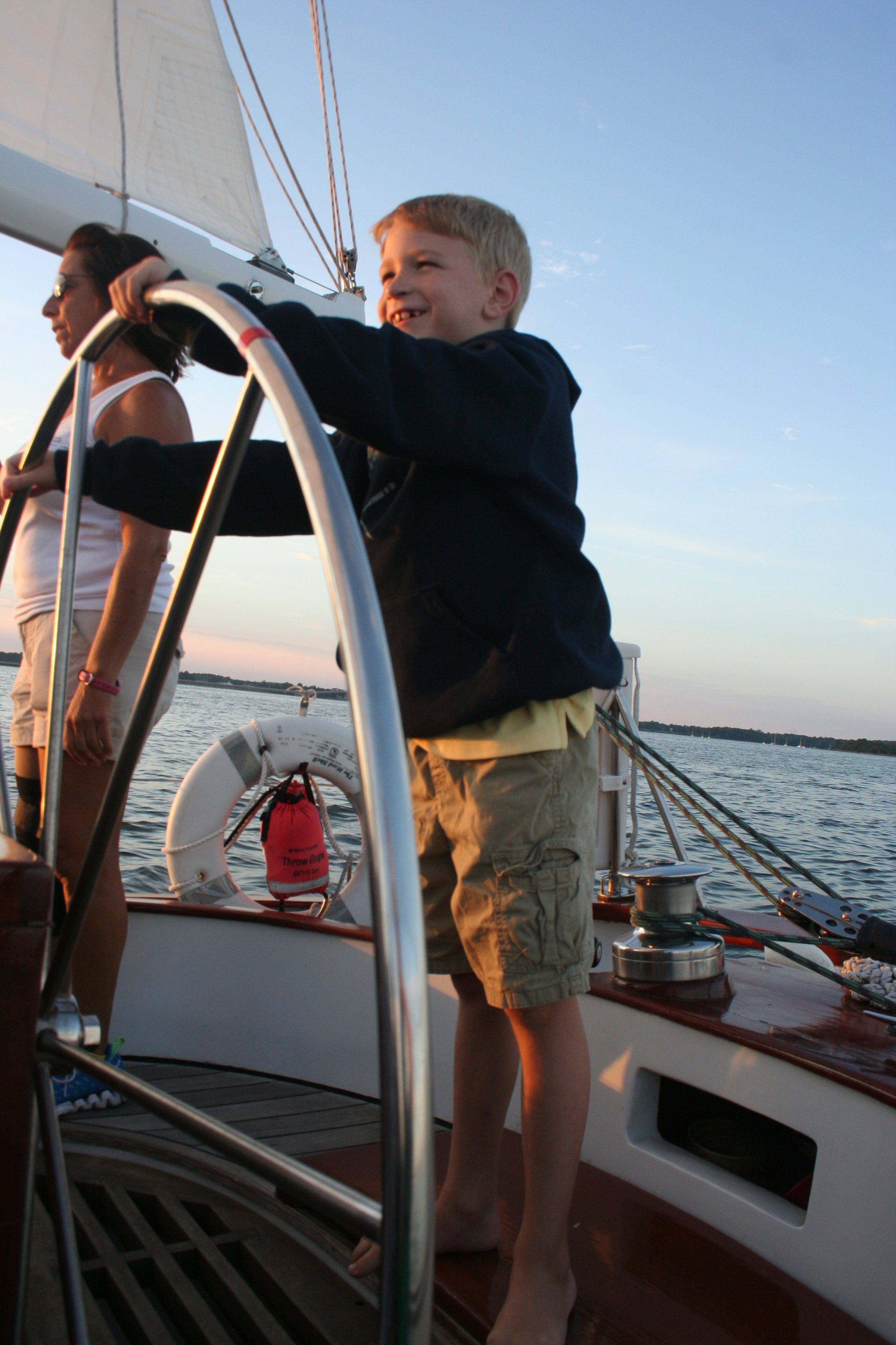 Young boy steering the schooner with captain supervision