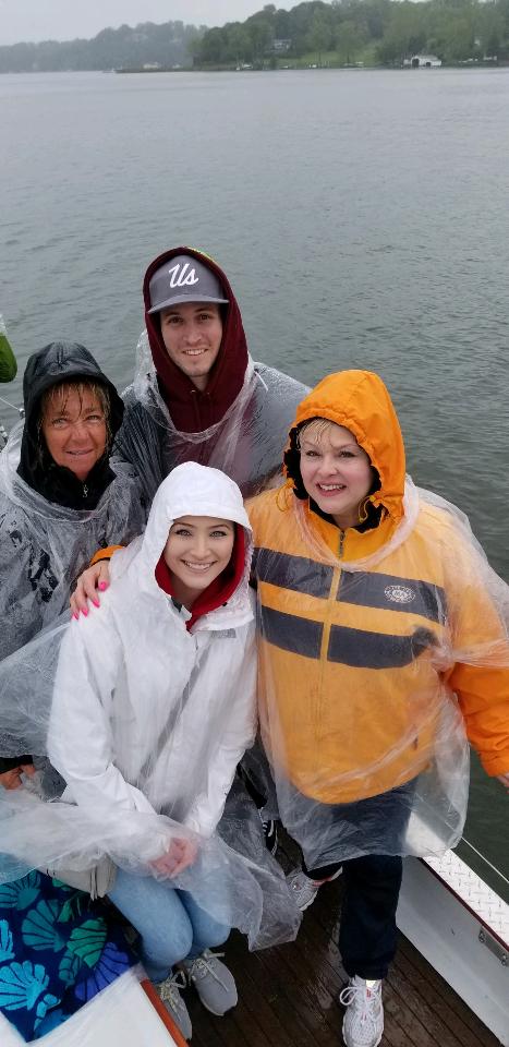 Four guests wearing clear ponchos and sailing in the rain