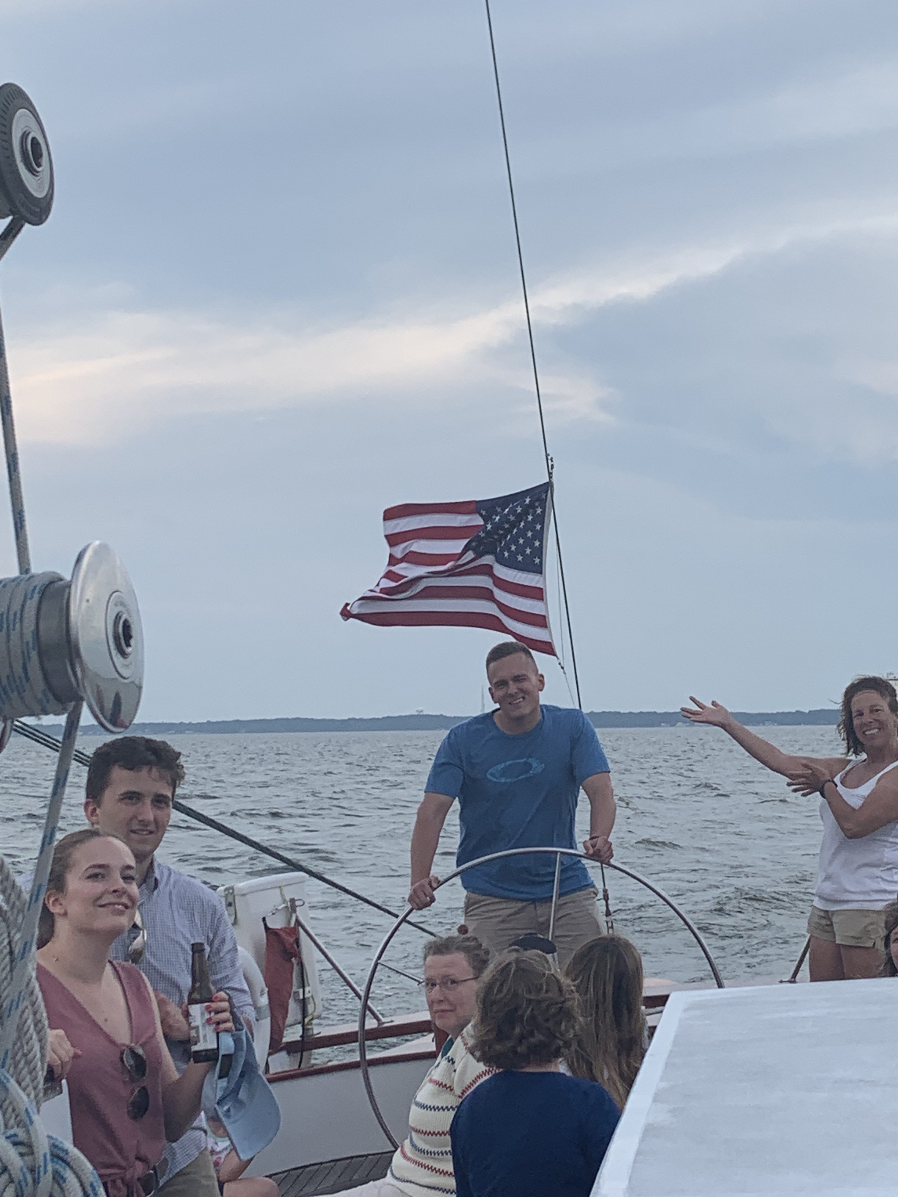 Man steering boat and smiling with American flag flying behind him