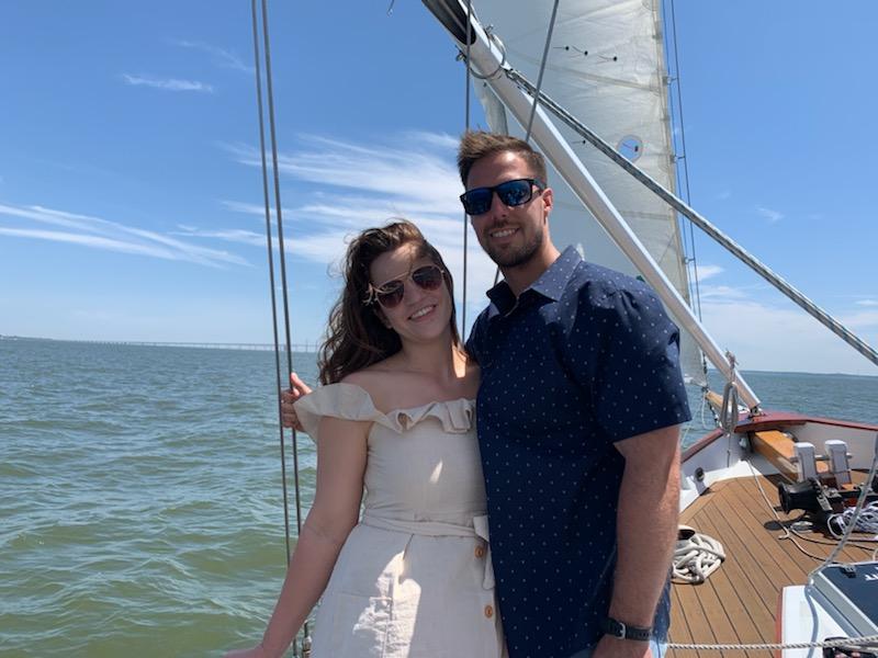 Smiling couple on deck posing in front of sail and blue water