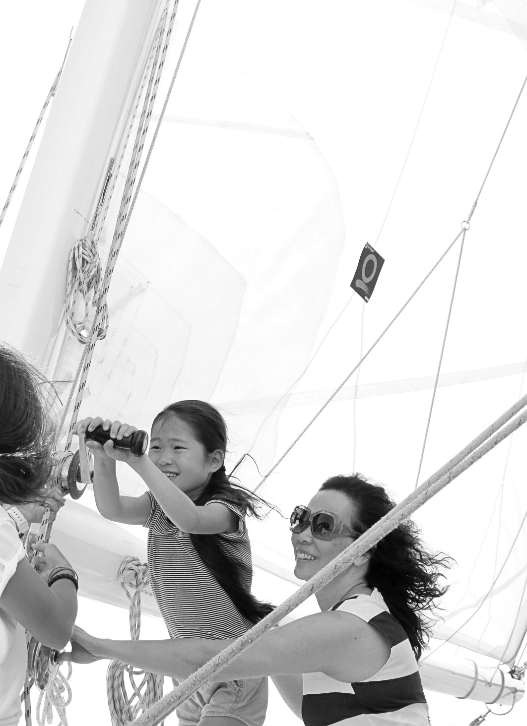 Black and white photo of a women and child raising the sails