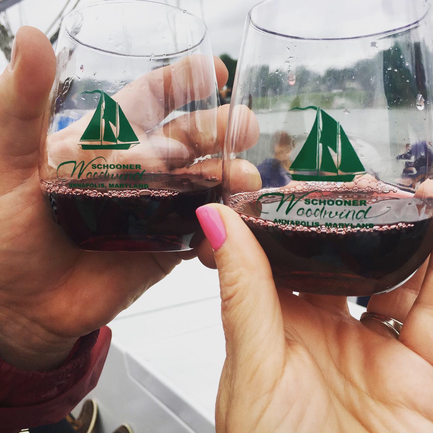 Two hands toasting red wine in glasses