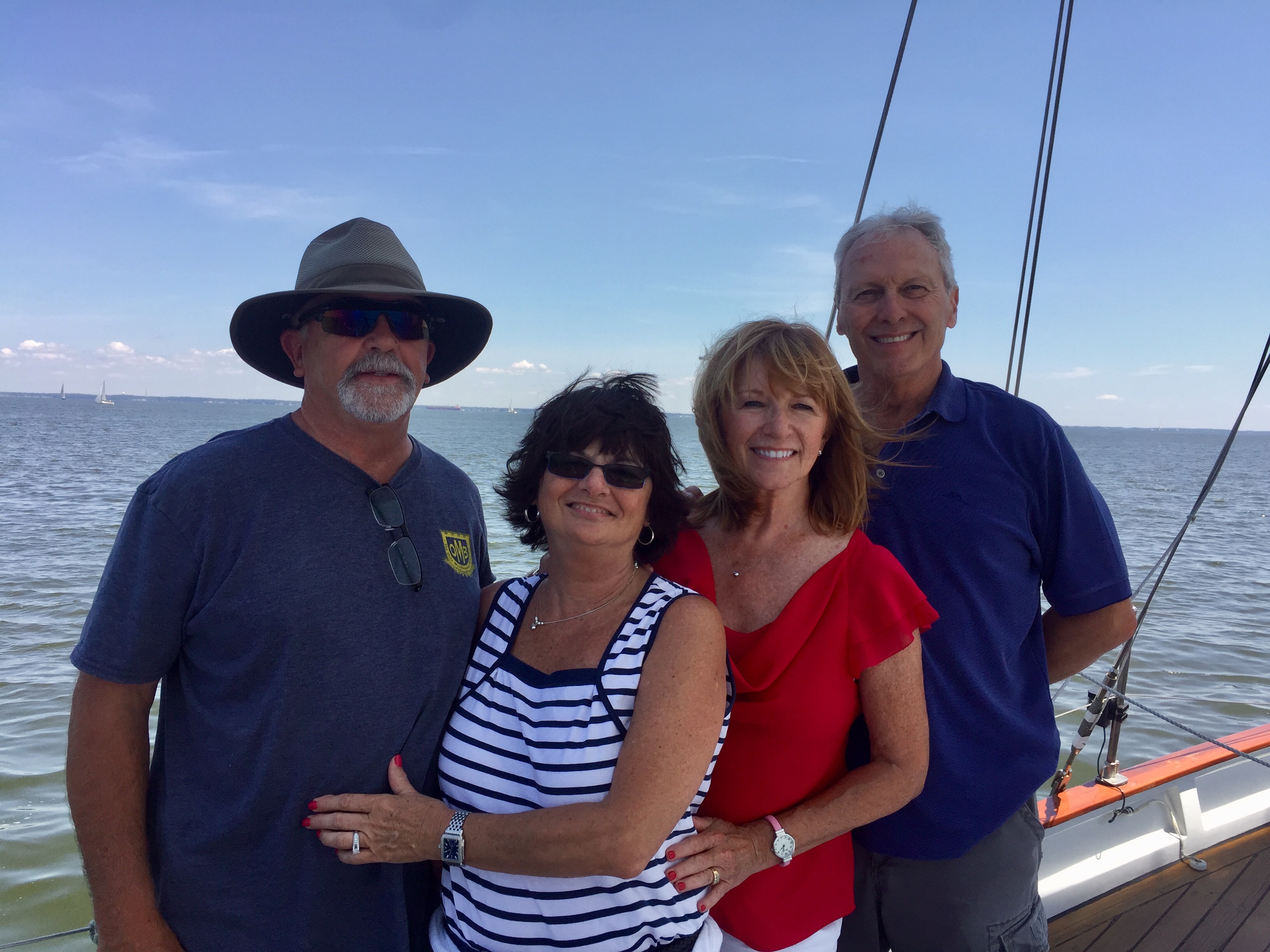 Two couples smiling on their sail posing in front of the water