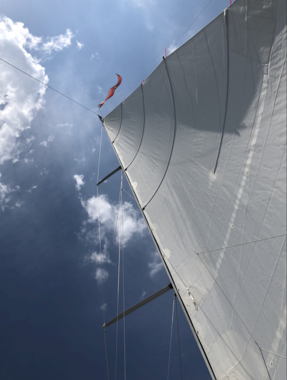 Looking up at the Mainsail to blue skies with puffy white clouds