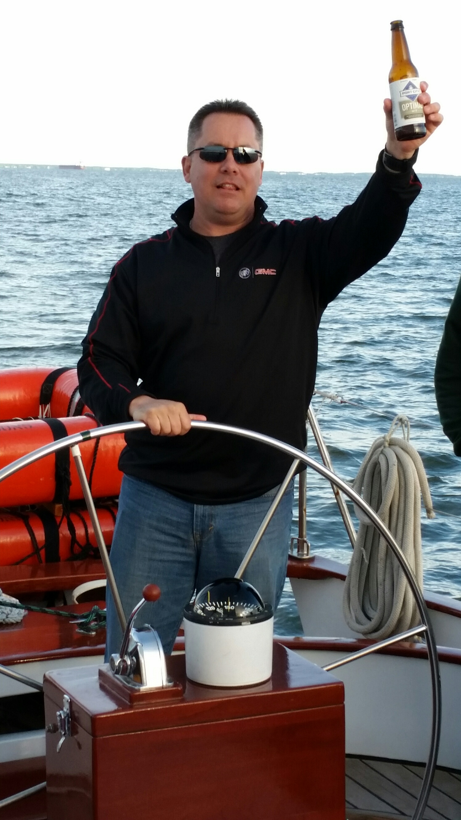 Guest steering schooner and cheering with a beer bottle