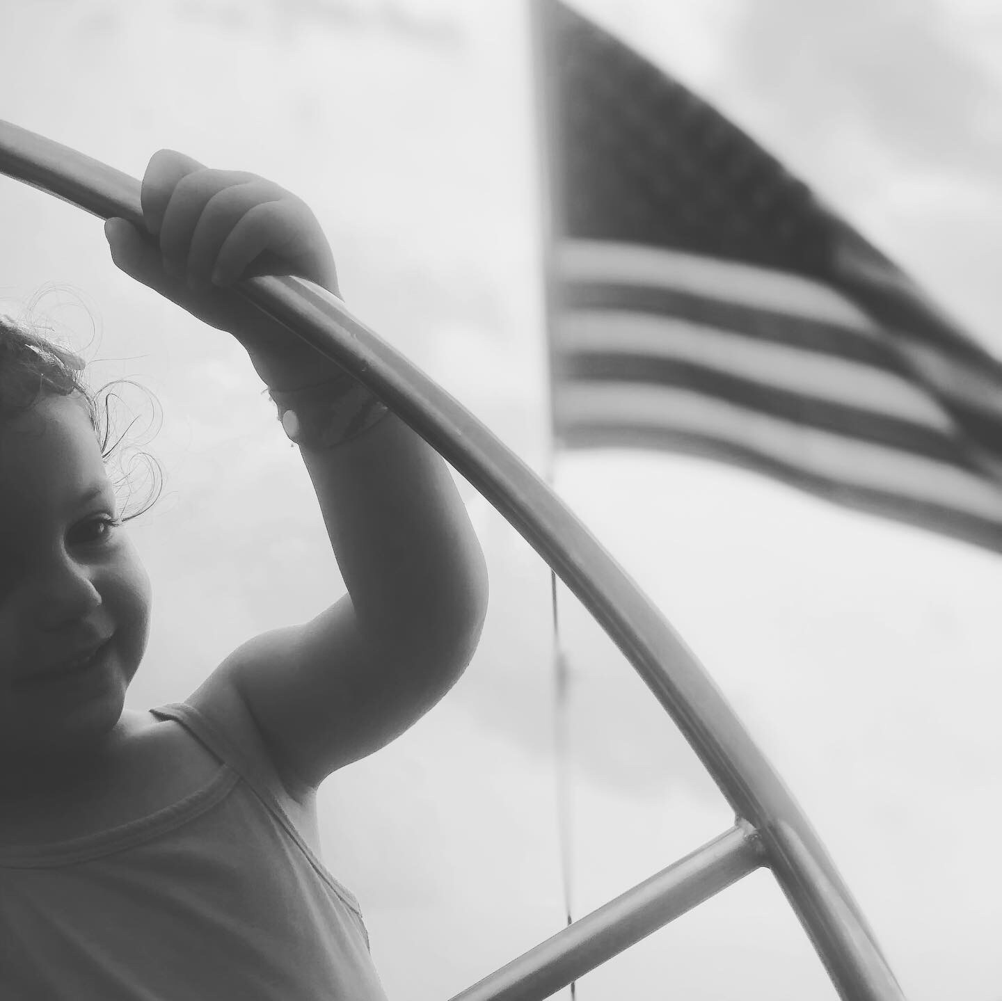 Black and white photograph of little one steering the helm of the schooner