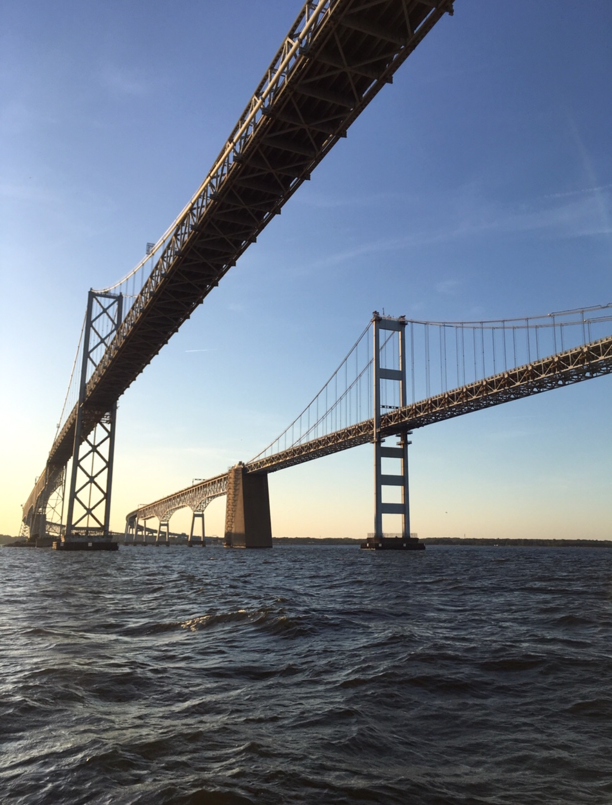 Both spans of the Bay Bridge with blue skies and water