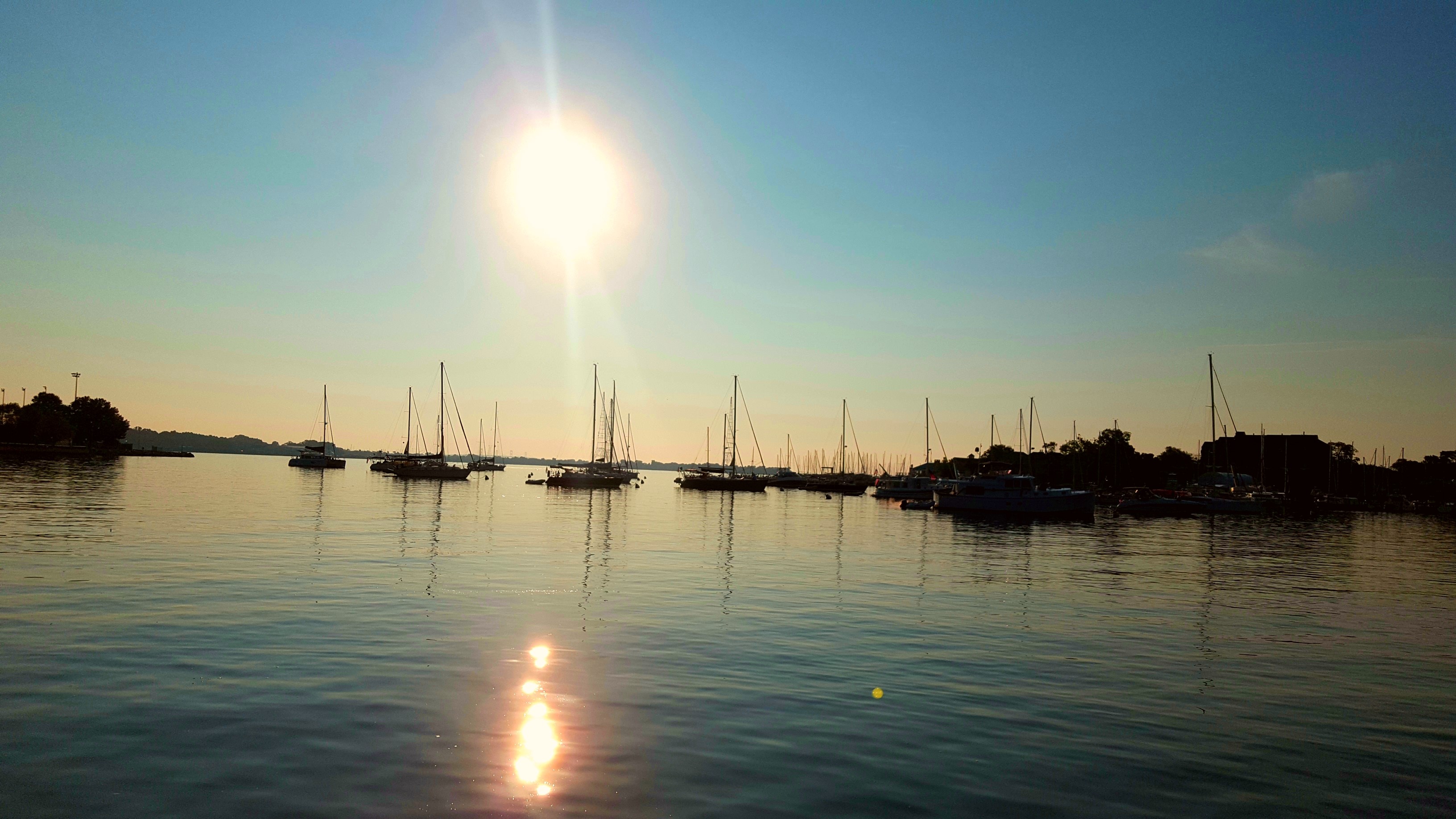 Sun coming up over the calm waters and moored boats in the harbor