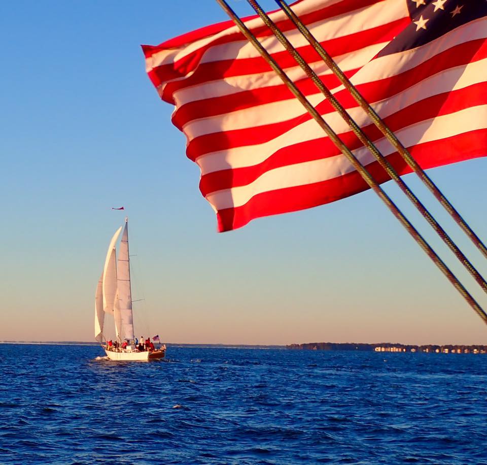 Bright blue waters and skies surround the schooners with American Flag flying